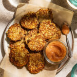 A plate of potato pancakes with a jar of applesauce.