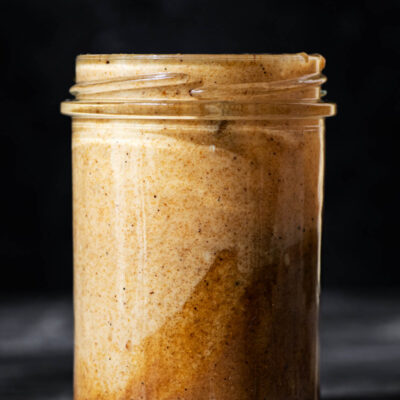 A glass jar, front view, filled with a tahini dressing.