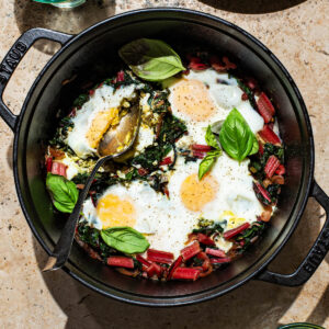 Baked eggs in a heavy pot with swiss chard and basil.