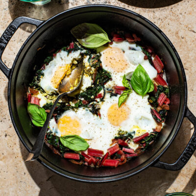 Baked eggs in a heavy pot with swiss chard and basil.