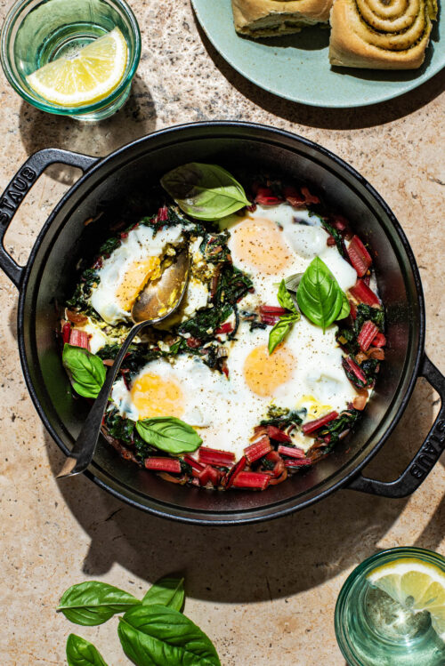 Baked eggs in a heavy pot with swiss chard and basil.