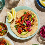 Two plates with mushroom and pepper filled tortillas, toppings in small bowls around.