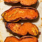 Roasted sweet potatoes cut-side up in hard light.