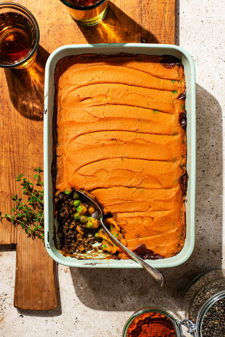 A lentil pie topped with sweet potato mash, one serving removed from the baking dish.