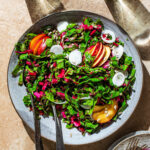 A chard salad with sliced nectarine, onion, and sunflower seeds in direct light.