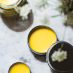 Three containers of lip balm with white flowers.