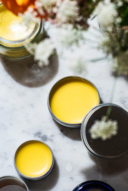 Three containers of lip balm with white flowers.