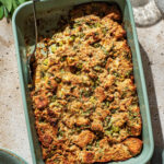 Top-down view of a rectangular dish of bread stuffing with a scoop removed.