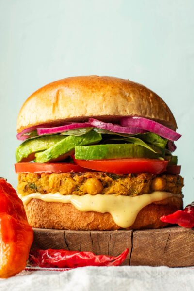 A chickpea patty burger topped with vegetables and pickled onions on a bun.