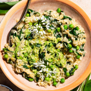A rice dish with pesto and peas mixed in, topped with wild garlic flowers.
