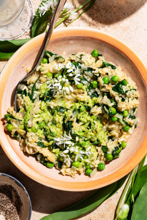 A rice dish with pesto and peas mixed in, topped with wild garlic flowers.