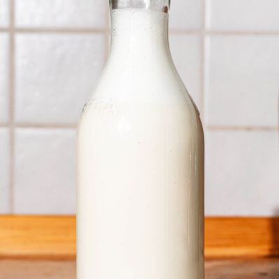 A glass bottle of nut milk on a kitchen counter.