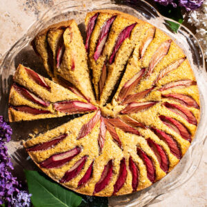 A rhubarb-topped cake with three slices cut, each on a slight angle.