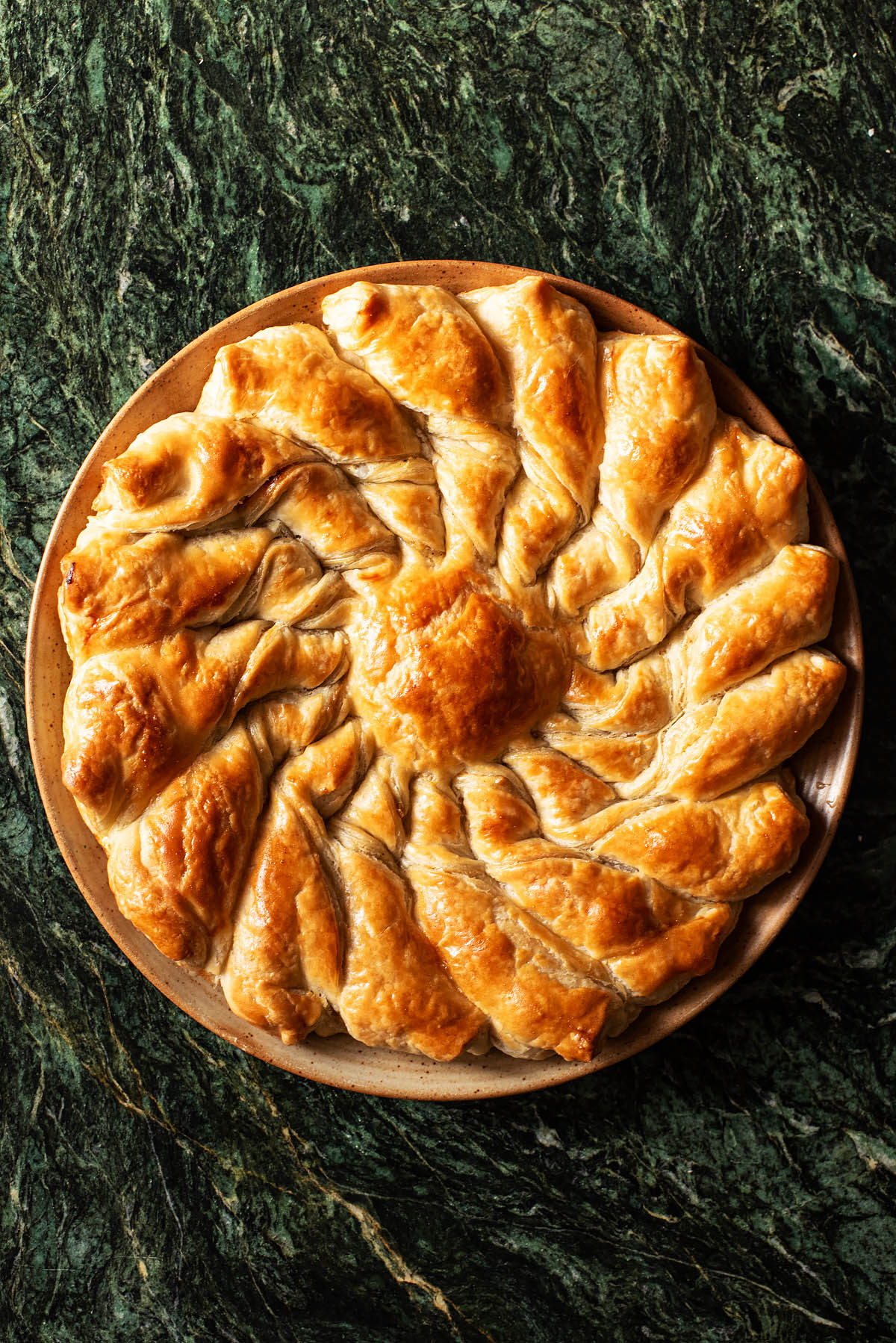 Round pull-apart pastry on a plate on green marble.