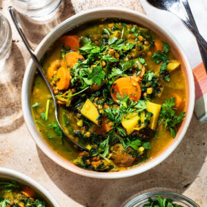 A bowl of carrot and potato soup topped with fresh parsley.