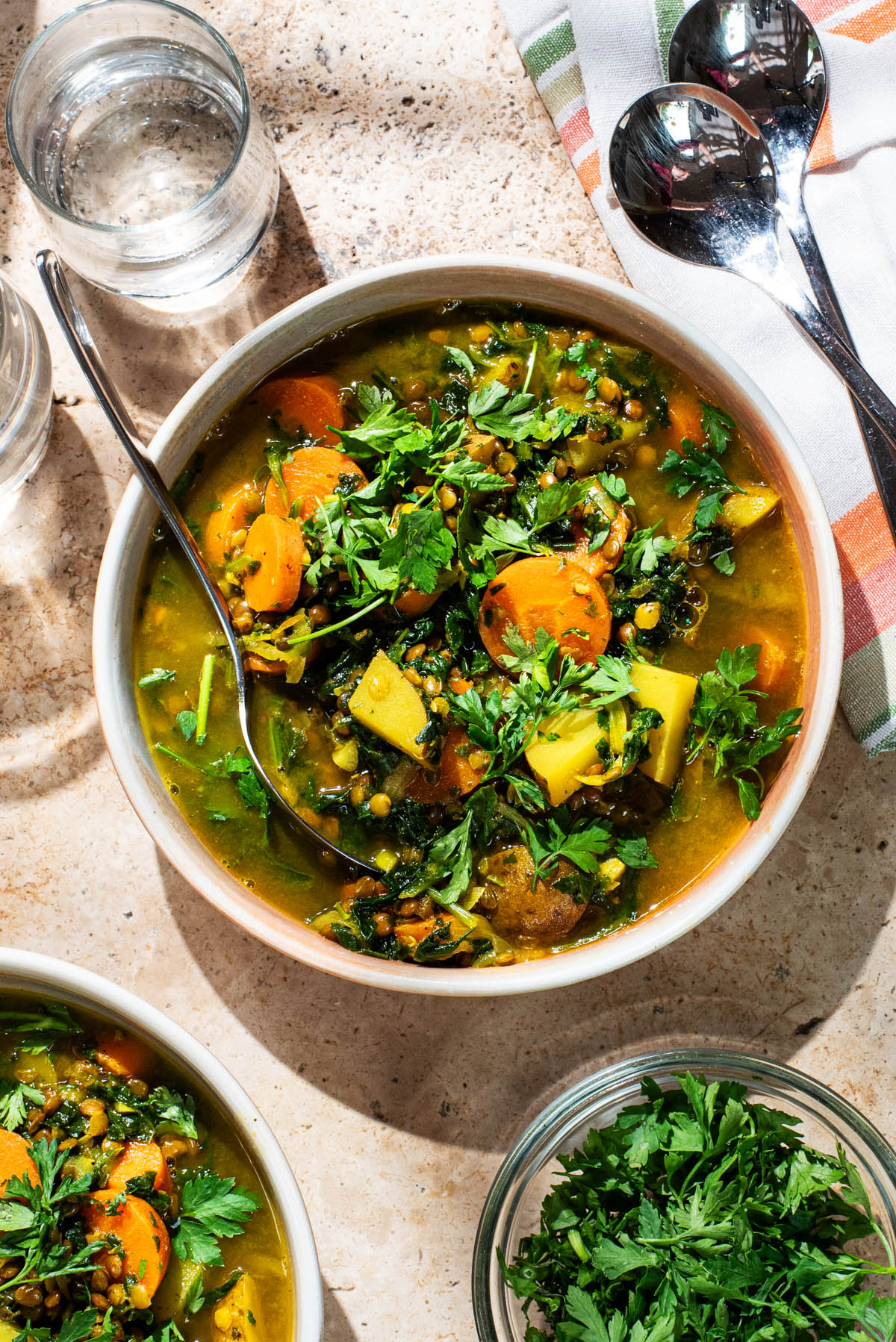 A bowl of carrot and potato soup topped with fresh parsley.
