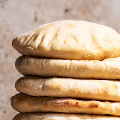 A stack of pitas on a small wooden cutting board.