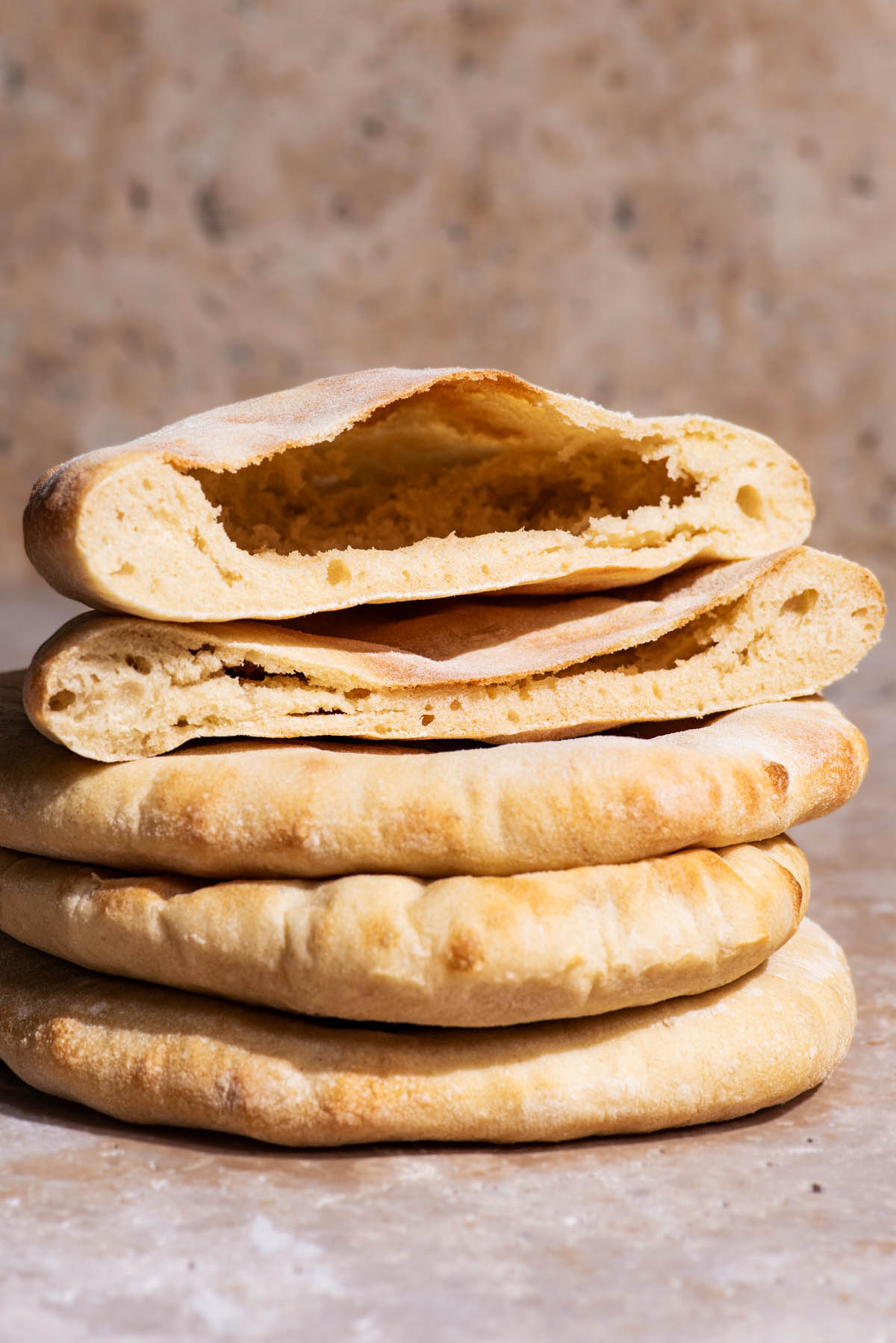 Pita breads stacked, with the top one halved to show interior.