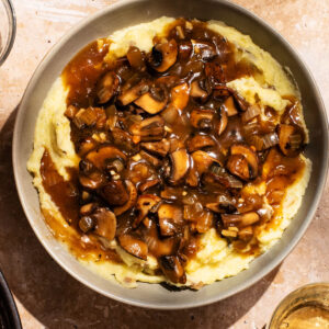 A bowl full of mashed potatoes topped with mushroom gravy.