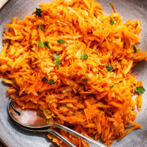A large serving bowl filled with shredded carrot salad.