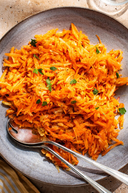 A large serving bowl filled with shredded carrot salad.