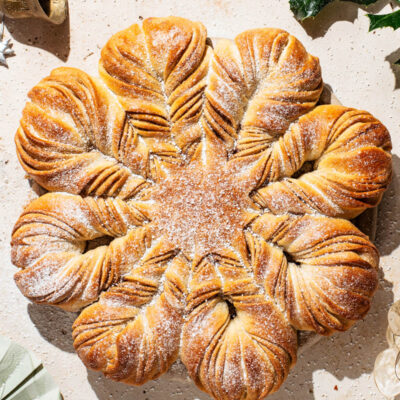 A loaf of star bread on a stone counter with holiday decorations in the corners.