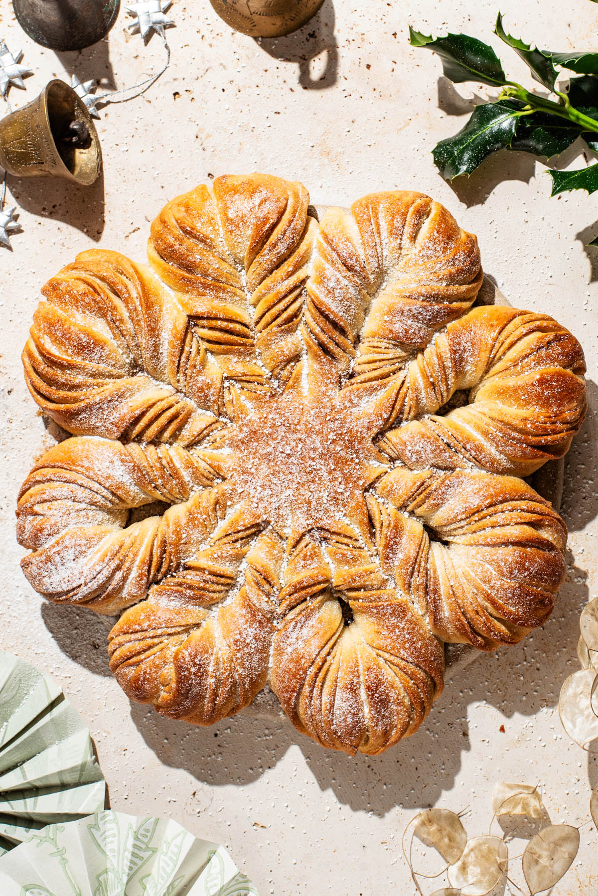 A loaf of star bread on a stone counter with holiday decorations in the corners.