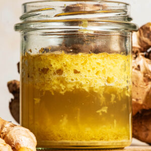 Close up of fermented shredded ginger floating in the water mixture in a glass jar.