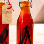 Small glass bottles of vanilla extract with pieces of vanilla beans inside.