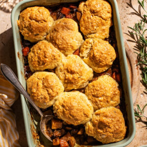 Biscuit-topped vegetable pie in a rectangular baking dish, one scoop removed.