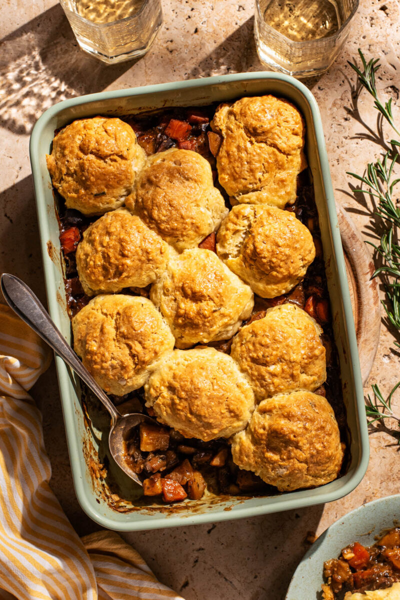 Biscuit-topped vegetable pie in a rectangular baking dish, one scoop removed.