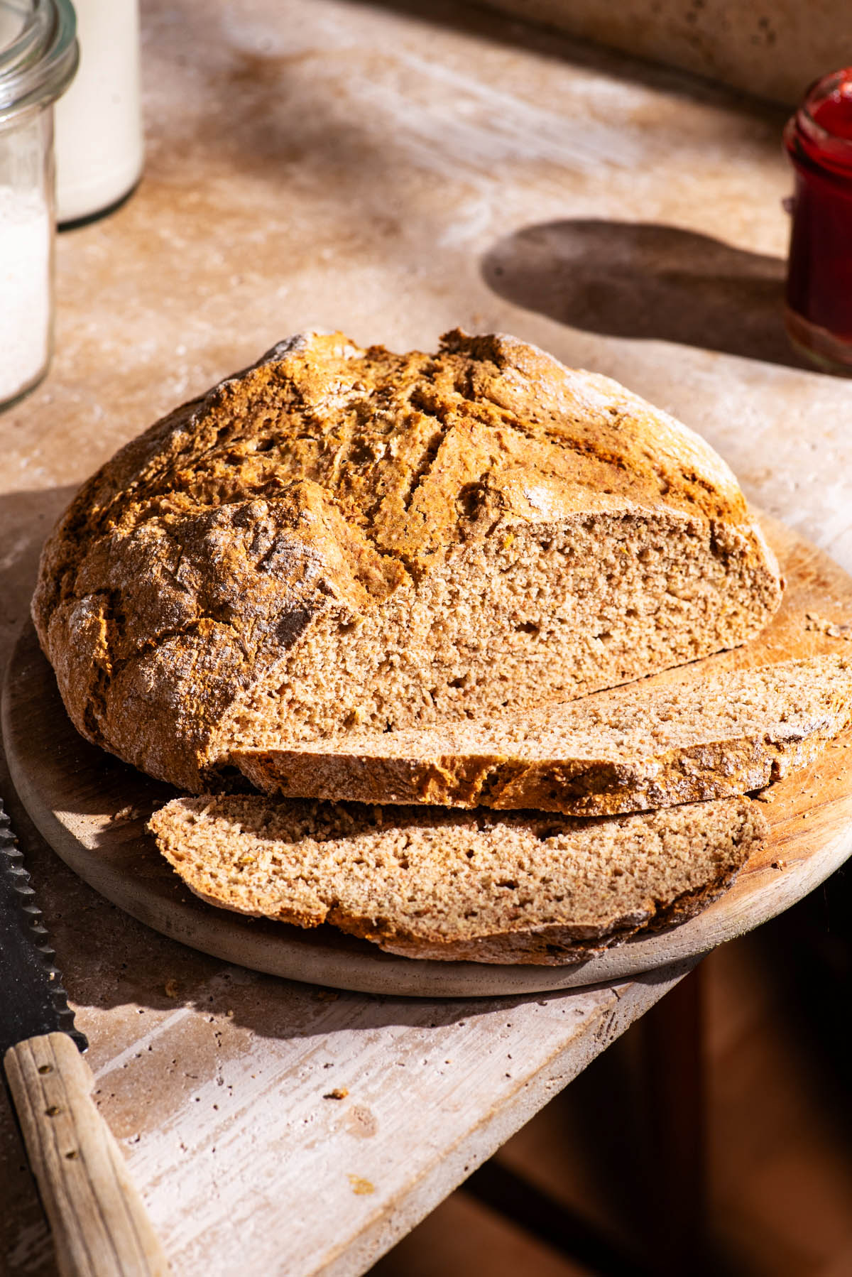 A round loaf of soda bread on a cutting board with two slices cut.
