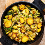 Cooked cabbage and potato rounds in a cast iron pan.
