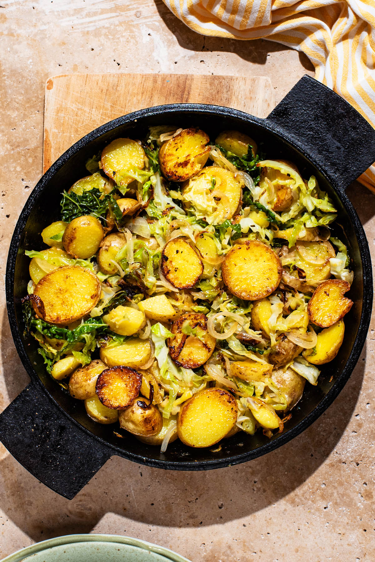 Cooked cabbage and potato rounds in a cast iron pan.