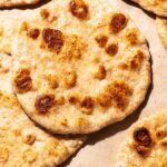 Several golden flatbreads on parchment paper.