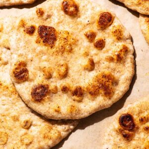 Several golden flatbreads on parchment paper.