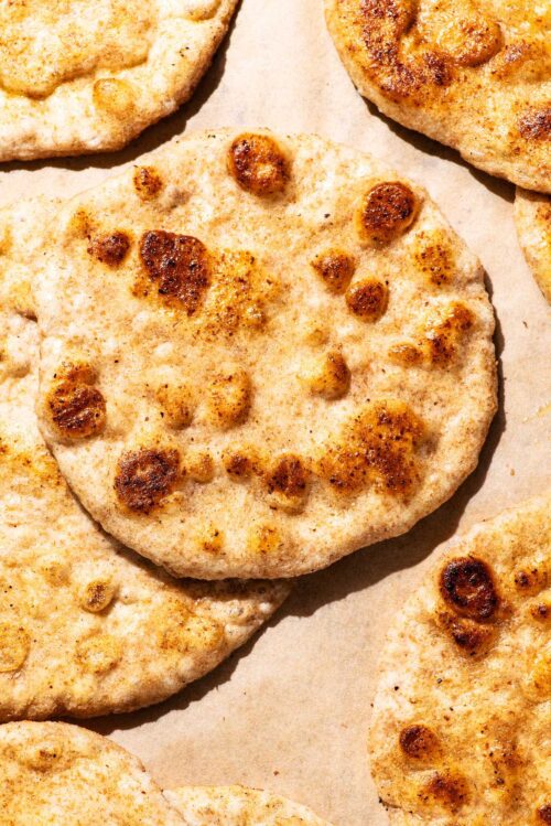 Several golden flatbreads on parchment paper.