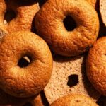 Several golden brown bagels, some halved to show interior texture.