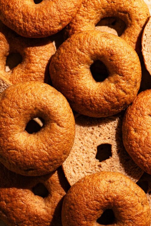 Several golden brown bagels, some halved to show interior texture.