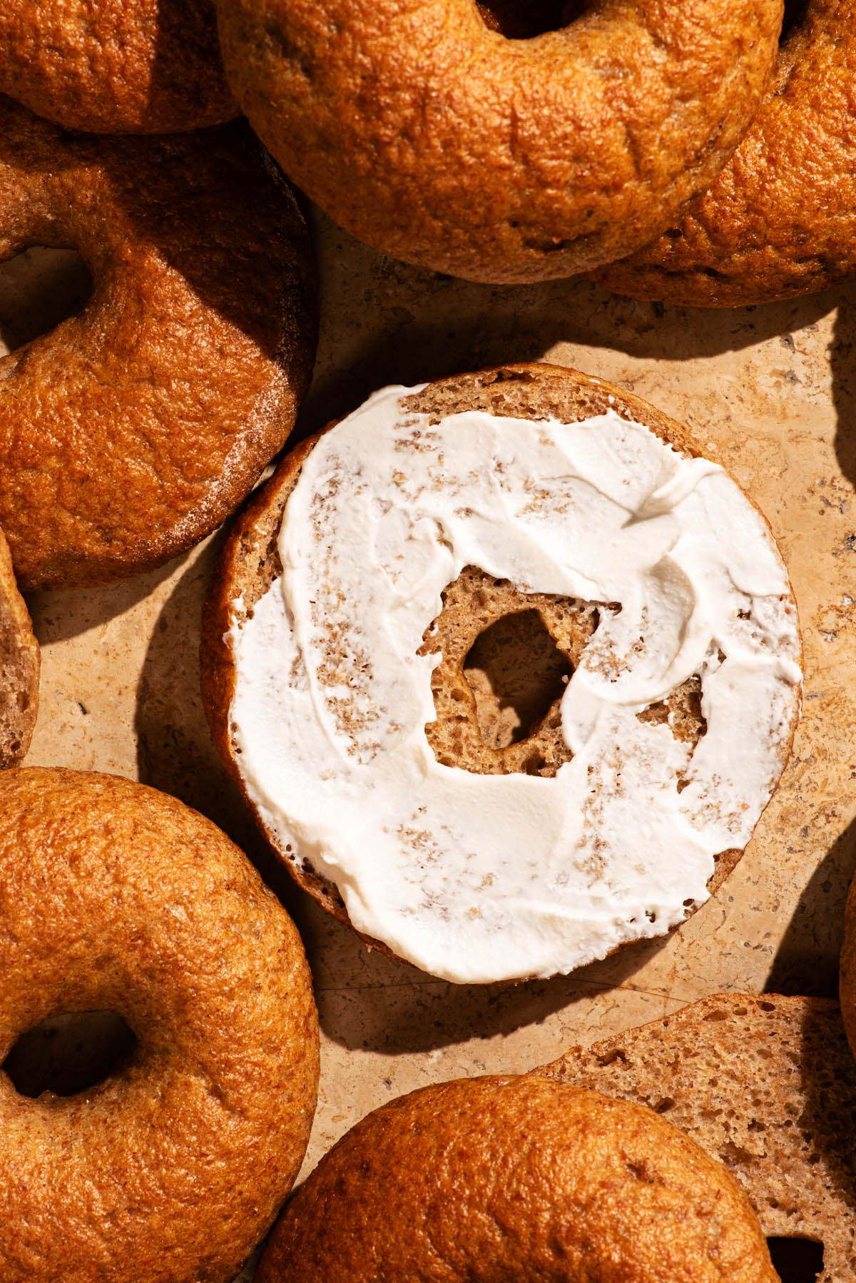 Several bagels, one halved with cream cheese on in.