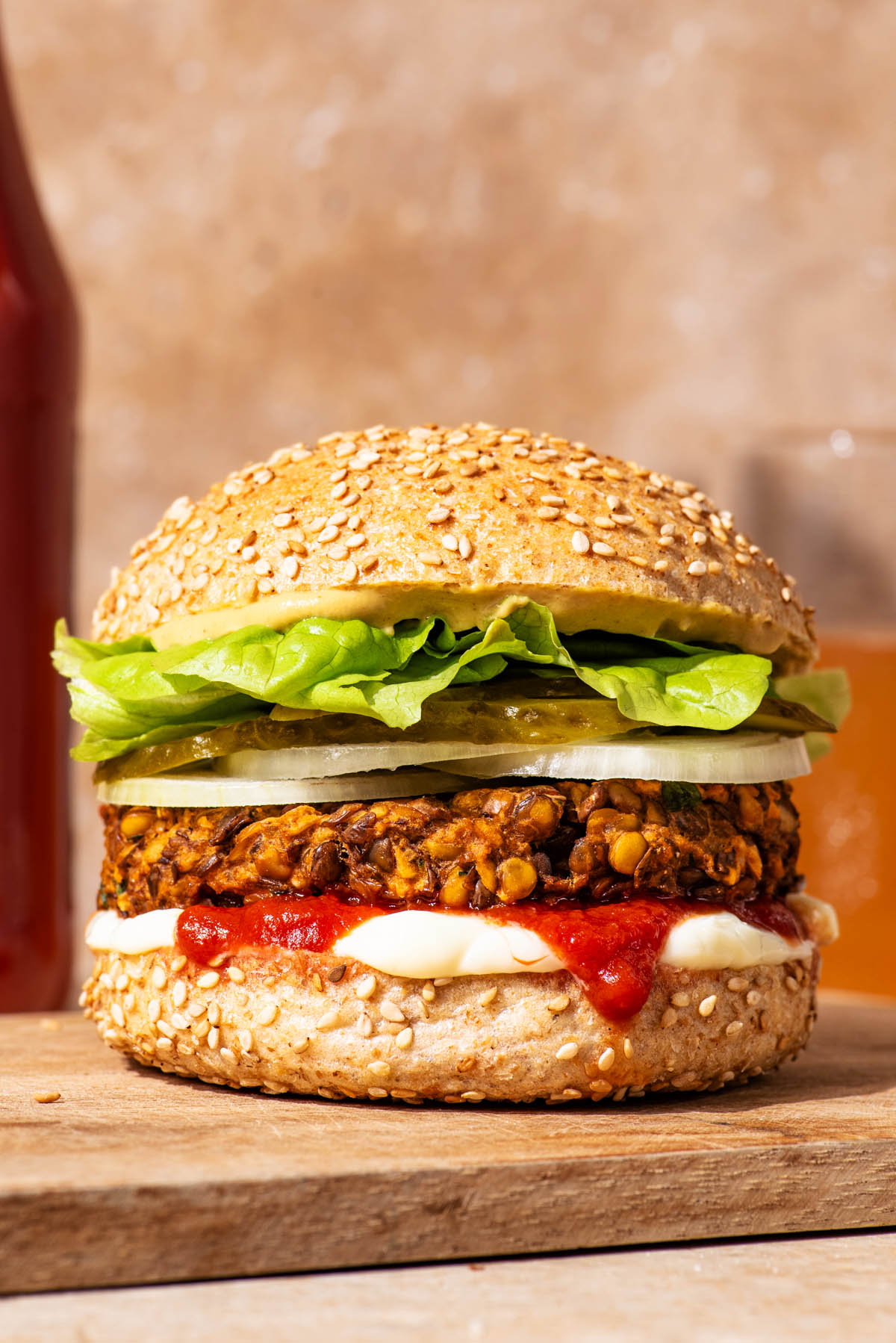 Vegetarian lentil burger on a bun with sauces and vegetable toppings.