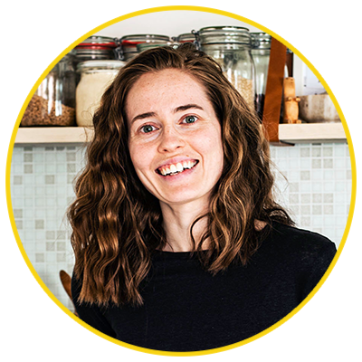 Woman smiling in a kitchen with open shelf at head height.