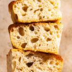 Three pieces of focaccia stacked on a small wooden cutting board.