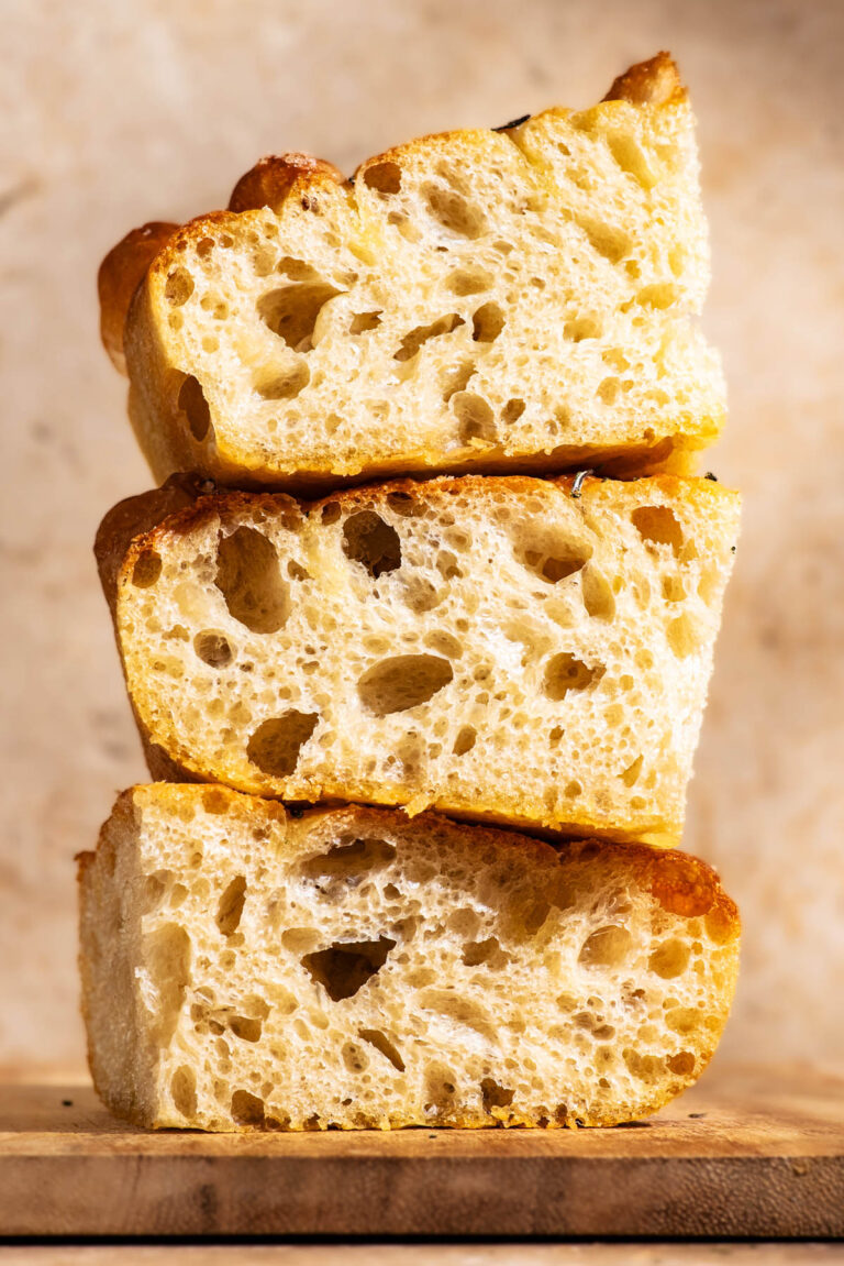 Three pieces of focaccia stacked on a small wooden cutting board.