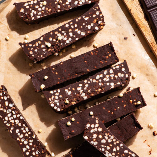 Chocolate bars with puffed millet, sliced on parchment paper.