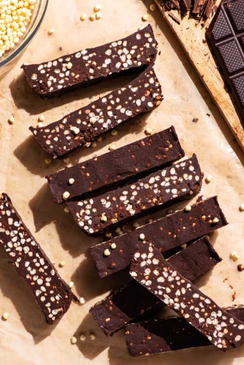Chocolate bars with puffed millet, sliced on parchment paper.