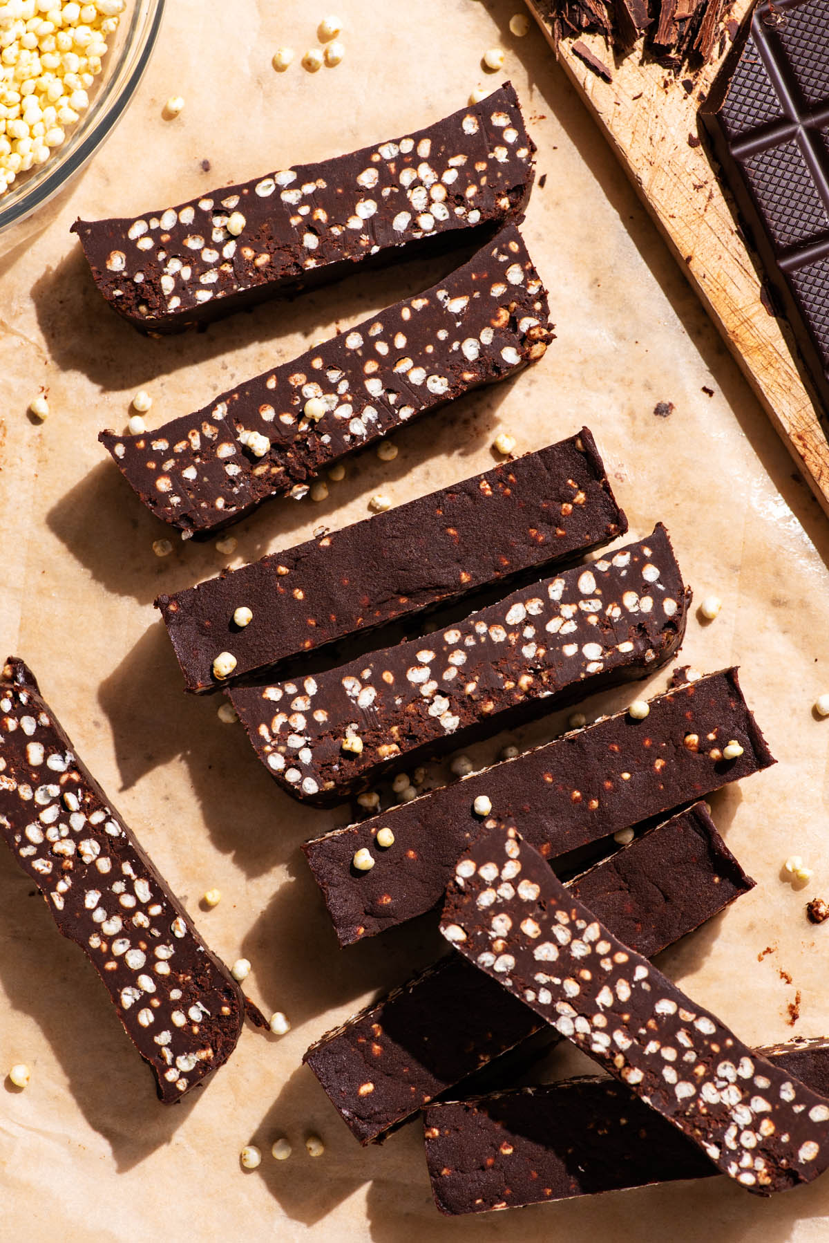 Chocolate bars with puffed millet, sliced on parchment paper.