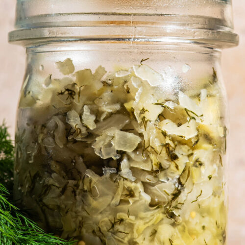 Lidded glass jar filled with dill sauerkraut.