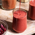 Dark pink smoothie on a stone surface.