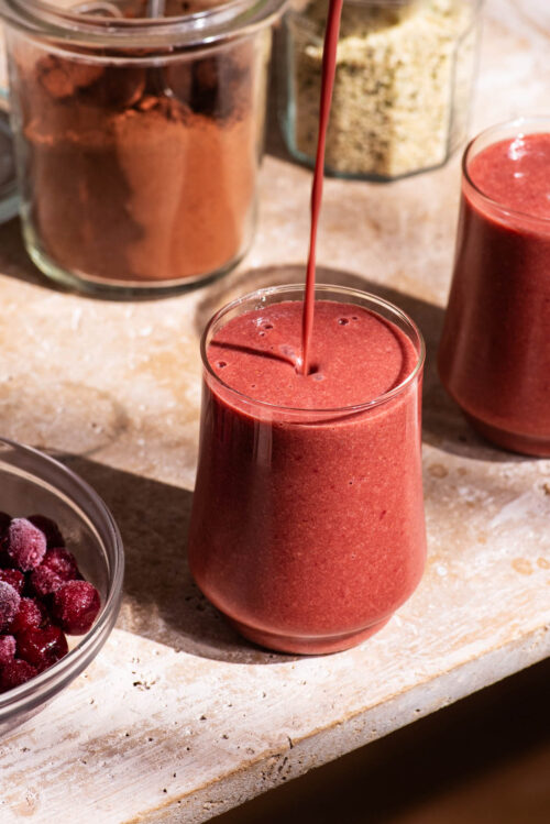Dark pink smoothie on a stone surface.